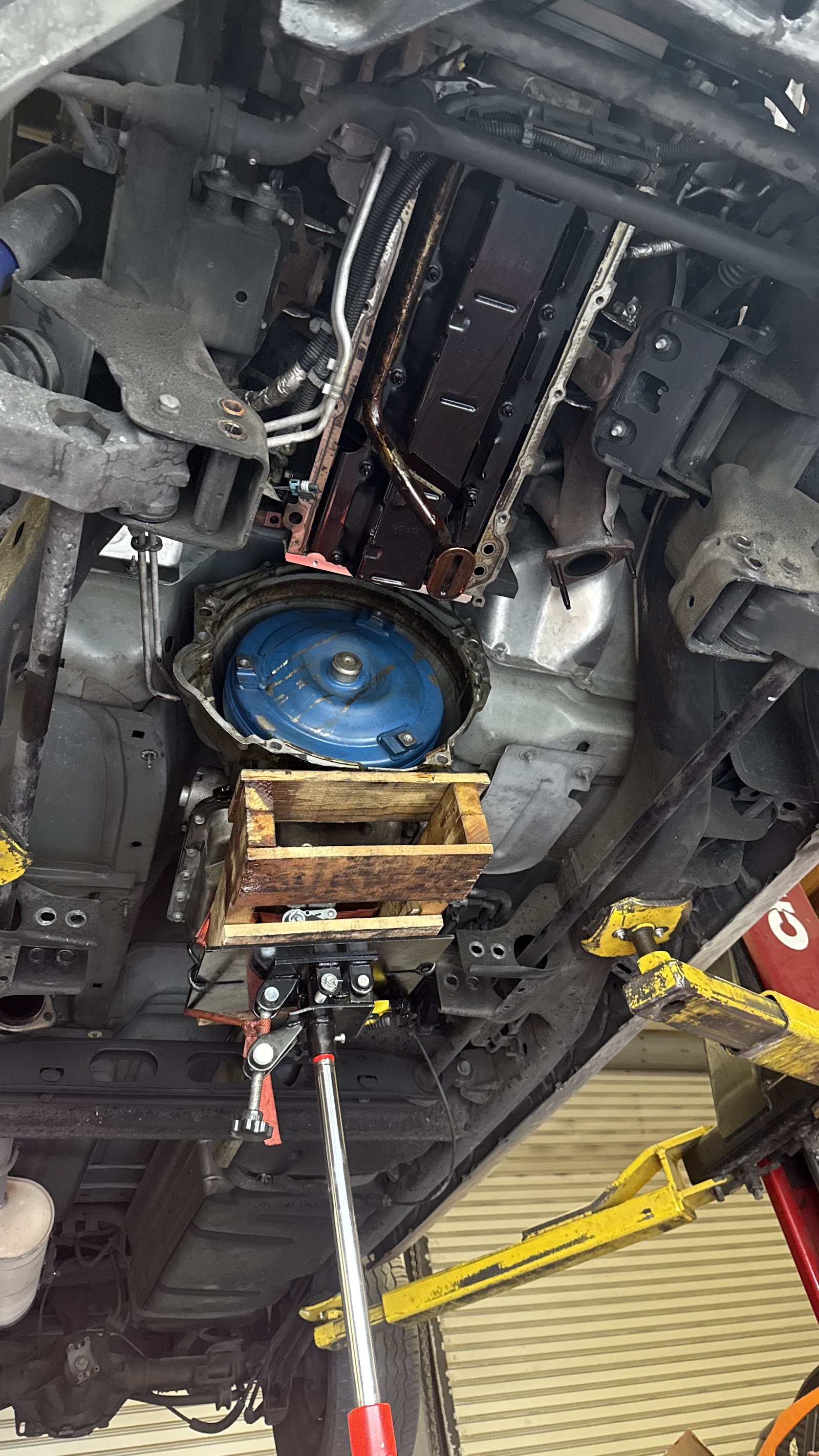 Transmission removal with the torque converter exposed, supported on a transmission jack